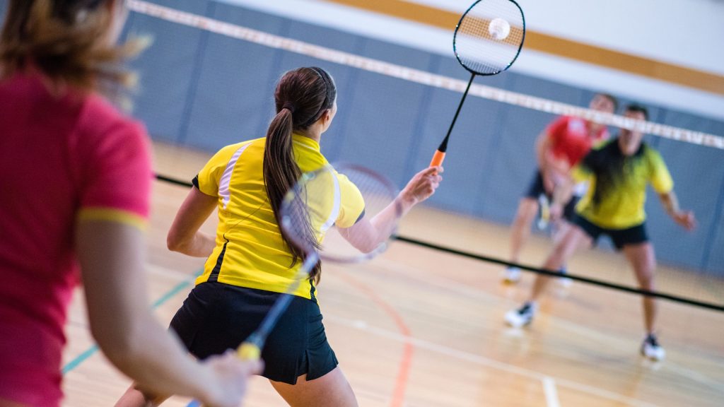 Jogadoras de badminton com raquetes na mão e jogando. O esporte estará nas Olimpíadas de Paris 2024