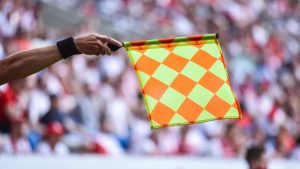 Bandeira de impedimento no futebol erguida por um profissional de arbitragem