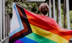 pessoa segurando a bandeira do orguljo LGBTQIAPN+