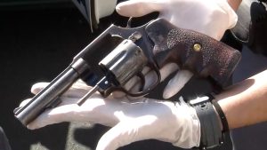 Arma sendo segurada por mão com luvas