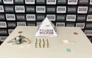 Arma, balas de arma e nota de 50 reais em cima de mesa, após operação