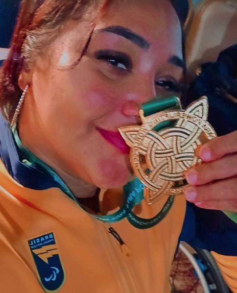 Atleta de halterofilismo Tayana Medeiros beijando medalha