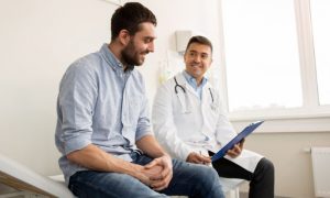 Homem à esquerda e médico à direita, durante consulta, visando a saúde