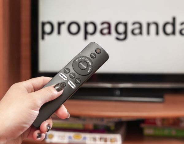 Televisão com texto propaganda eleitoral, mulher segurado controle remoto