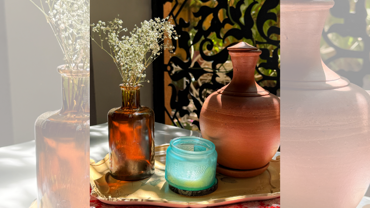 Objetos em cima da mesa: garrafa com flores, vela e garrafa de argila