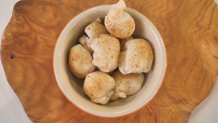 Bowl com pães de queijo em uma tábua de madeira