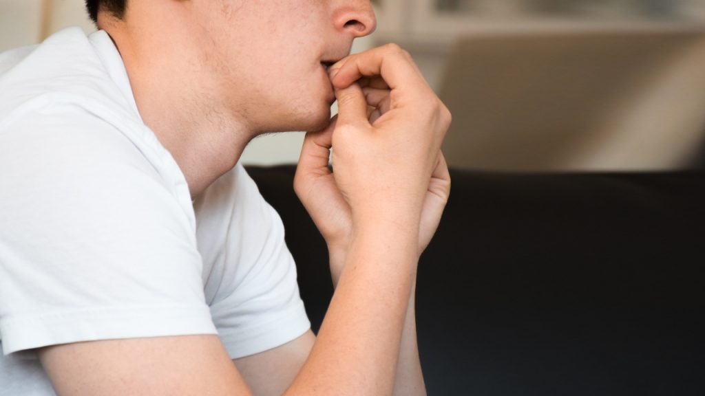 O que gera uma crise de ansiedade? homem roendo as unhas  O que gera uma crise de ansiedade