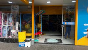 A porta de vidro da loja de brinquedos foi completamente destruída, deixando apenas cacos espalhados pelo chão. Crédito: Deborah Peres