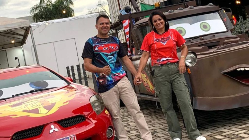 Veridiano posando ao lado da esposa, em frente às criações