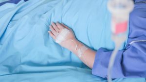 Mão de uma pessoa internada em hospital, recenedo soro na veia