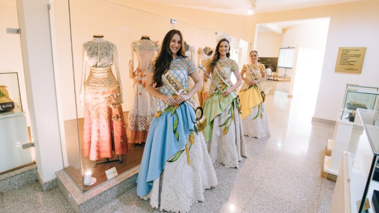 Corte eleita da Fenamilho 2025 posa com trajes típicos e faixas, sorrindo diante do Memorial do Milho em Patos de Minas. Corte eleita da Fenamilho 2025 posa com trajes típicos e faixas, sorrindo diante do Memorial do Milho em Patos de Minas.