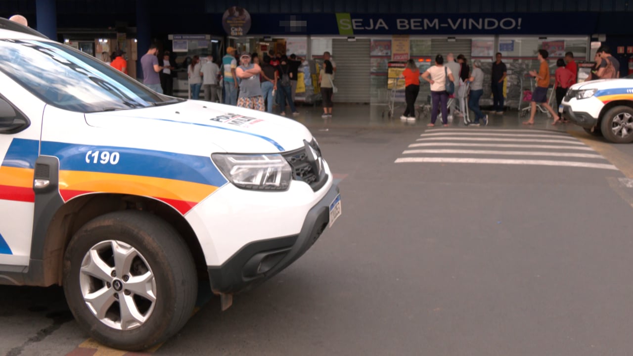 Veículo da Polícia militar em supermercado onde mulher foi esfaqueada, com grande movimentação de pessoas