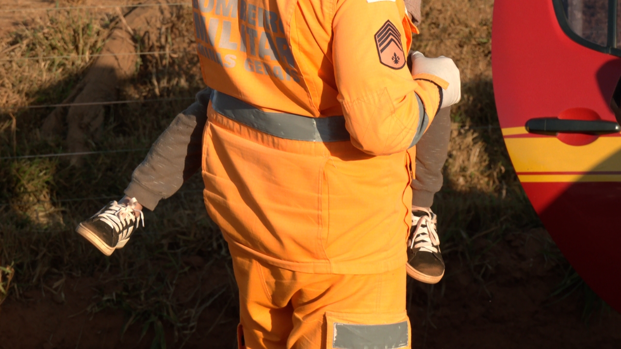 Bombeiro segurando criança vitima do acidente com van escolar