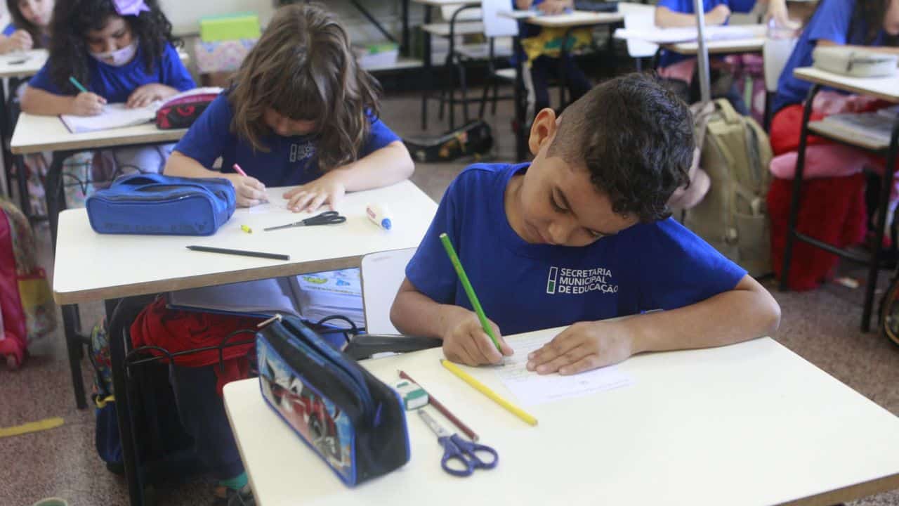 Inscrições escolares em Uberlândia. Alunos estudando em sala de aula com uniforme e material escolar na mesa