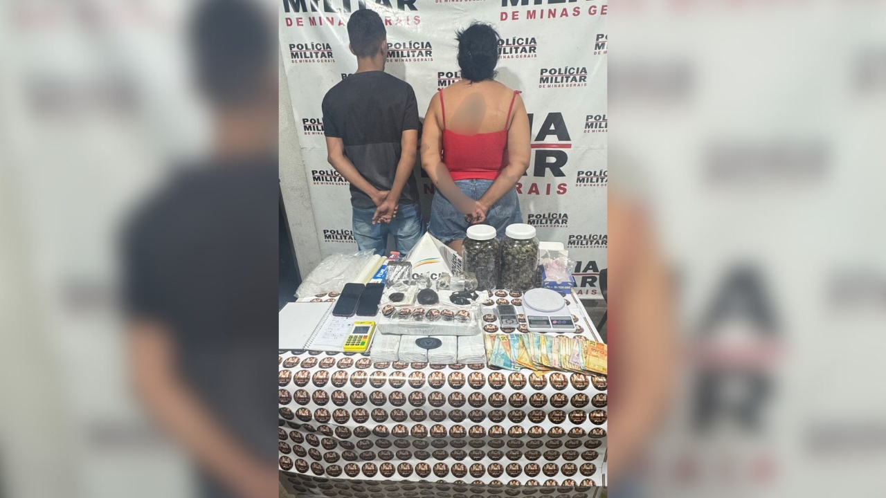 Foto da PM com o casal preso de costas, algemados e à frente os materias apreendidos encontrados do depósito de drogas e no carro do casal