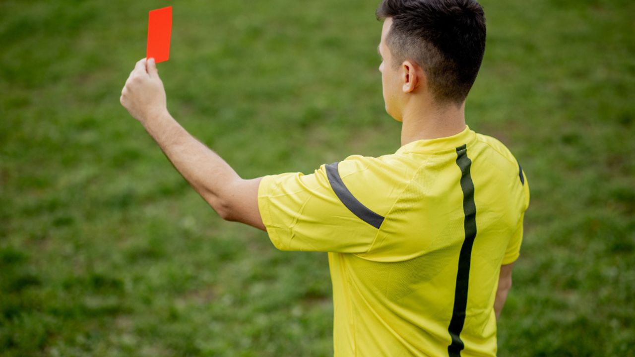 arbitro de futebol com uniforme amarelo com um cartão vermelho na mão no dia do arbitro