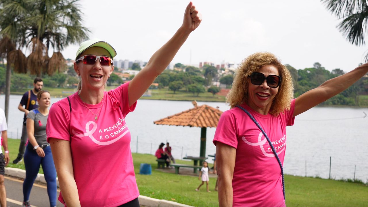 duas mulheres com os braços levantados participando da caminhada contra o câncer de mama em 2024 duas mulheres com os braços levantados participando da caminhada contra o câncer de mama em 2024
