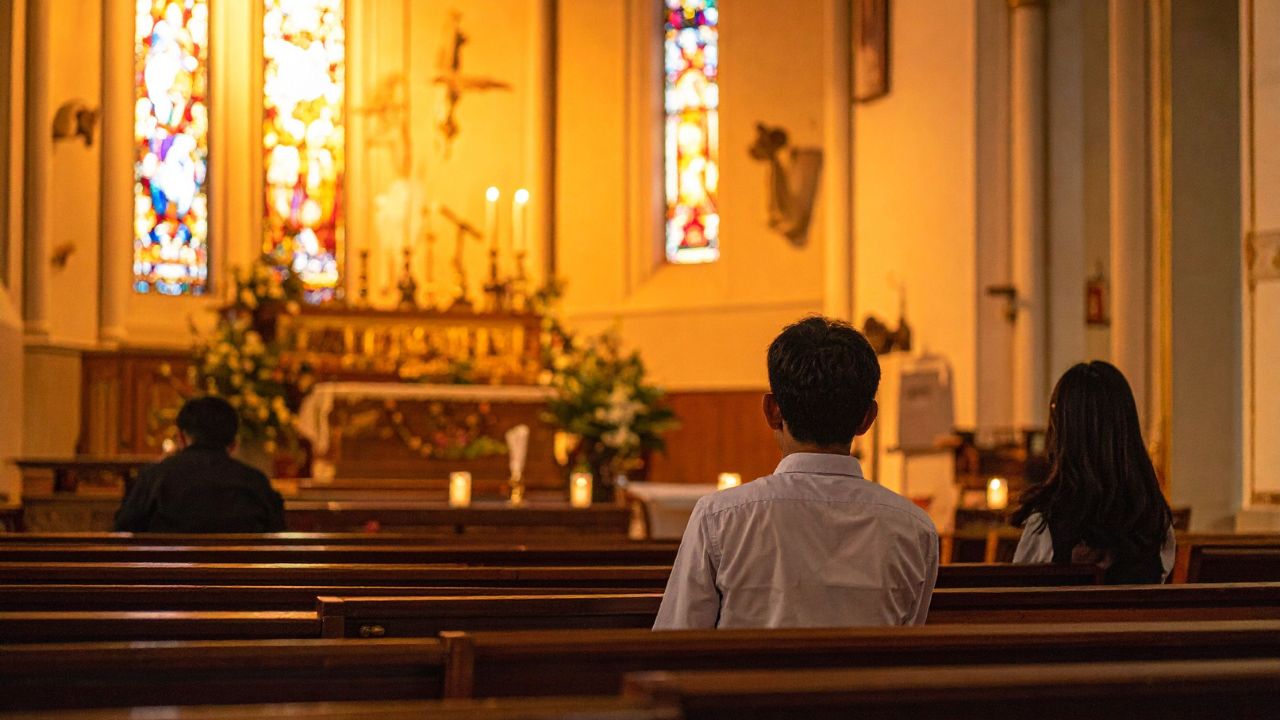 Fiéis em uma igreja católica, simbolizando o dia da padroeira dos endividados, Santa Edwiges